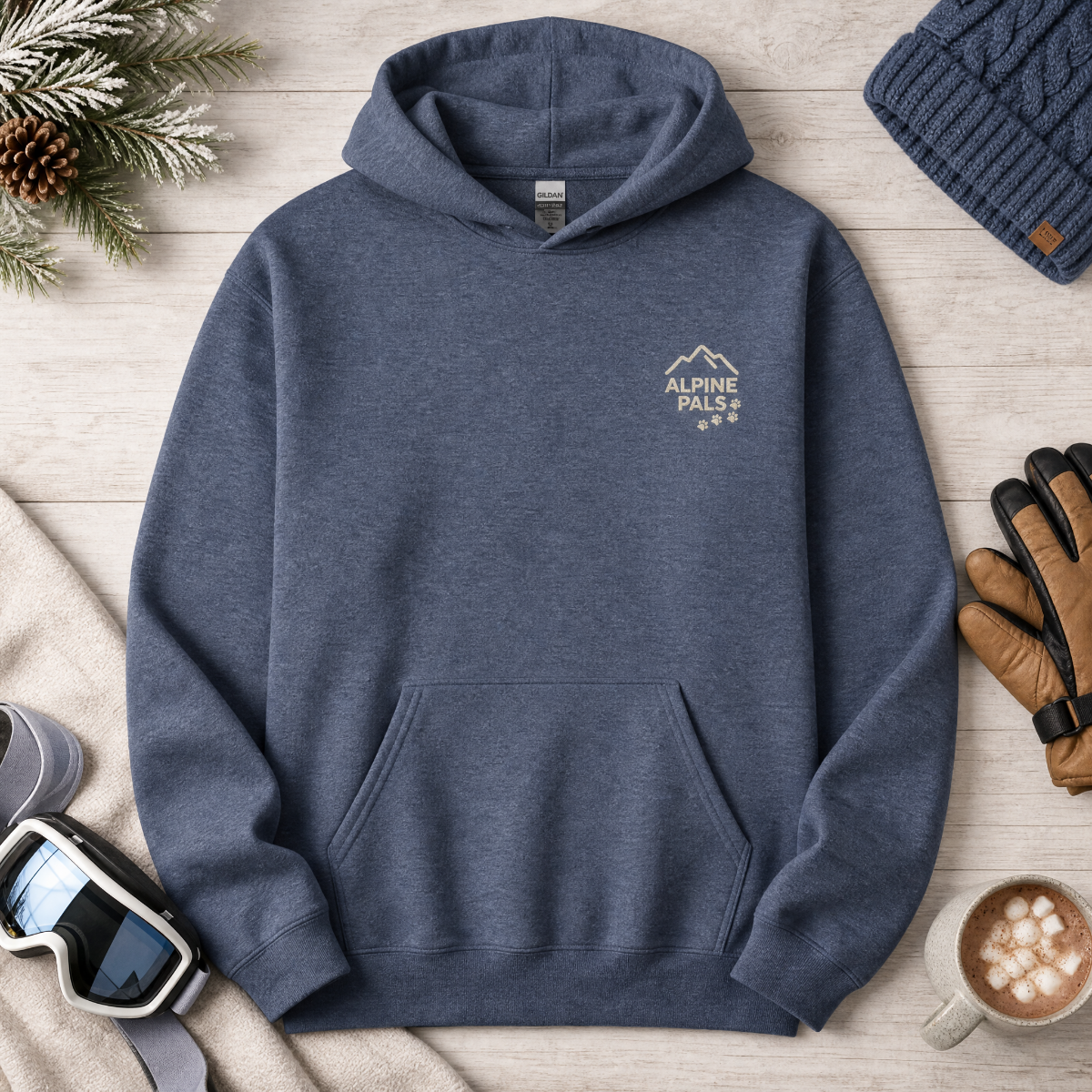 Heather sport dark navy hoodie with 'Alpine Pals' logo on a wooden surface with winter accessories.