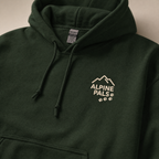 Forest green hoodie with 'Alpine Pals' logo on a neutral background