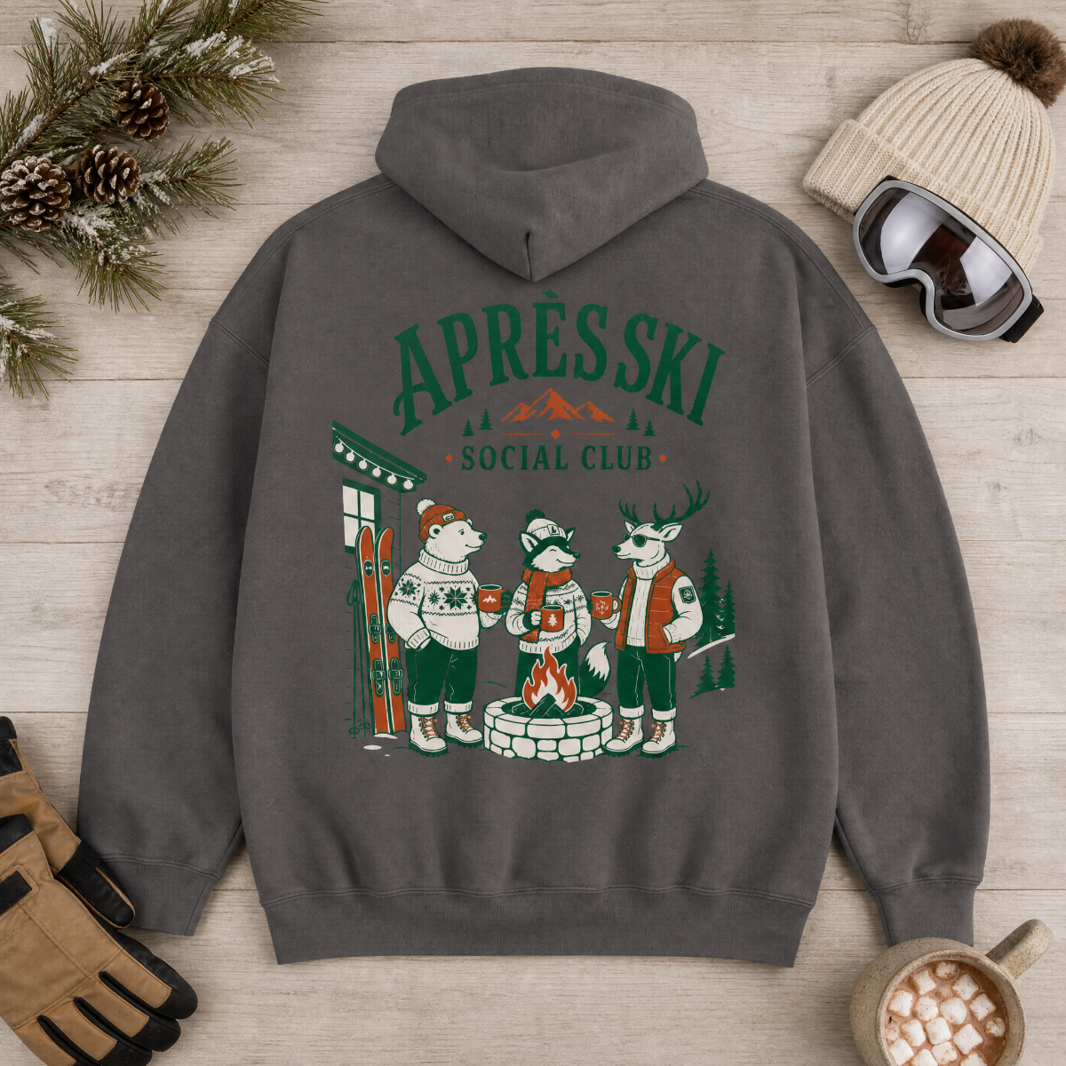 Charcoal gray hoodie with 'Après Ski Social Club' design on a wooden surface with winter accessories.