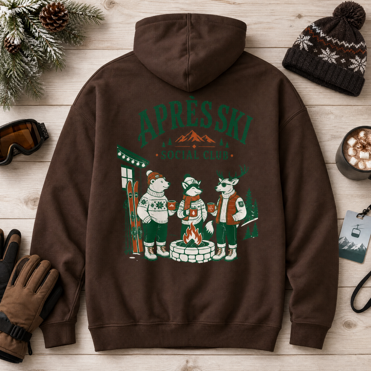 Dark chocolate brown hoodie with 'Après Ski Social Club' design on a wooden surface with winter accessories.