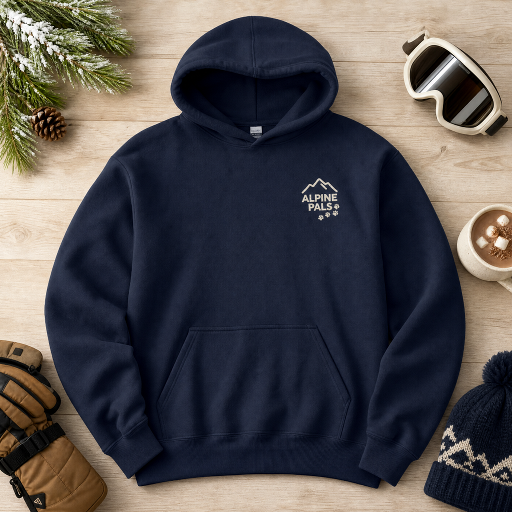 Navy blue hoodie with 'Alpine Pals' logo on a wooden surface with winter accessories.