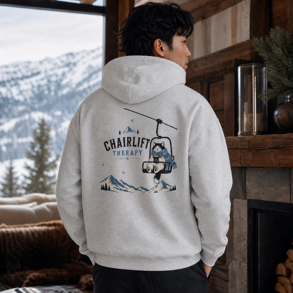 Person wearing a hoodie with 'Chairlift Therapy' design in a mountainous setting