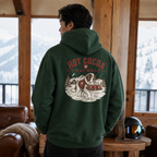 Person wearing a forest green hoodie with 'Hot Cocoa Patrol' design indoors.