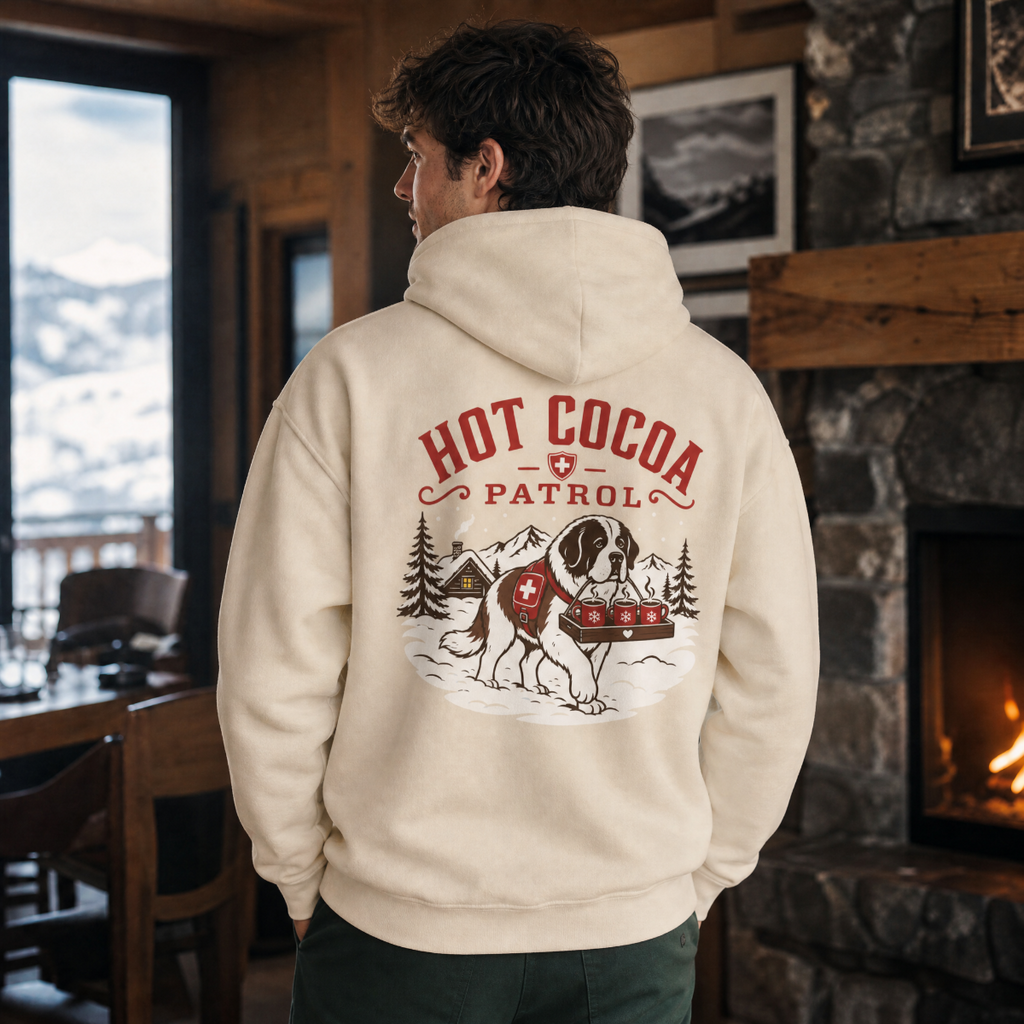 Person wearing a hoodie with 'Hot Cocoa Patrol' design in a cozy indoor setting.