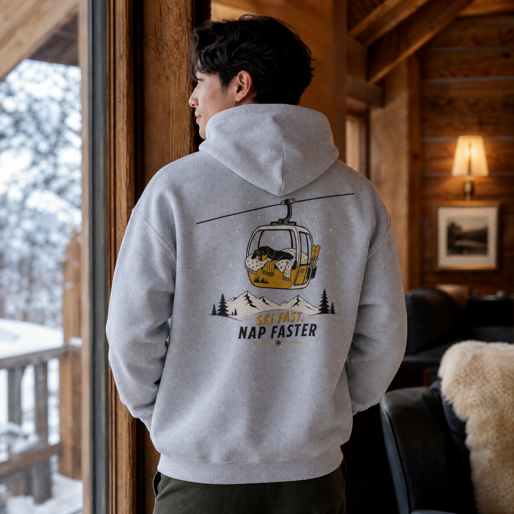 Person wearing a sport gray hoodie with a graphic design, standing in a cozy room with wooden walls and a snowy outdoor view.