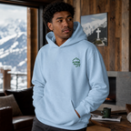 Person wearing a light blue hoodie with a logo in a room with a mountain view.