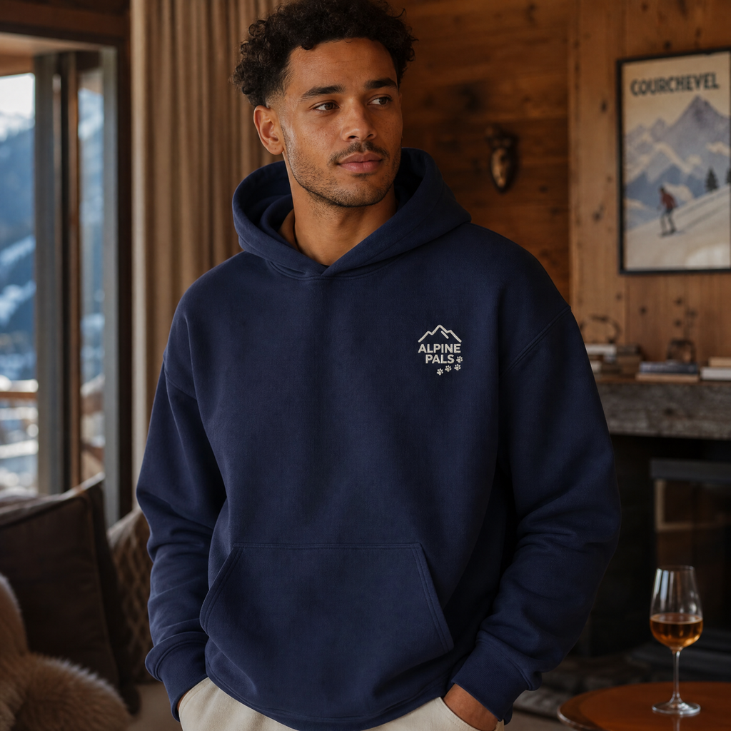 Man wearing a navy hoodie with a logo in a mountain-themed room