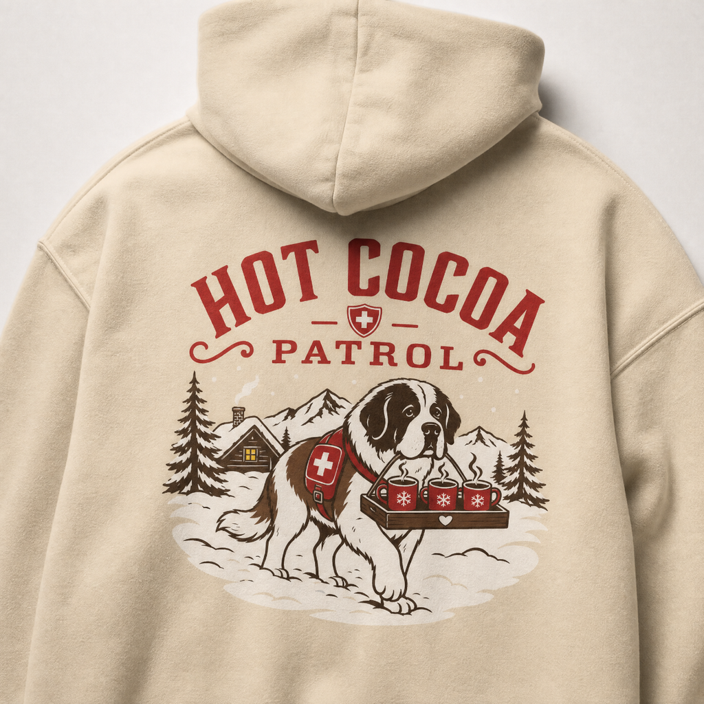 Sand colored hoodie with 'Hot Cocoa Patrol' graphic featuring a dog and hot cocoa on a tray.