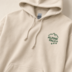 Sand colored hoodie with 'Alpine Pals' logo on a light background