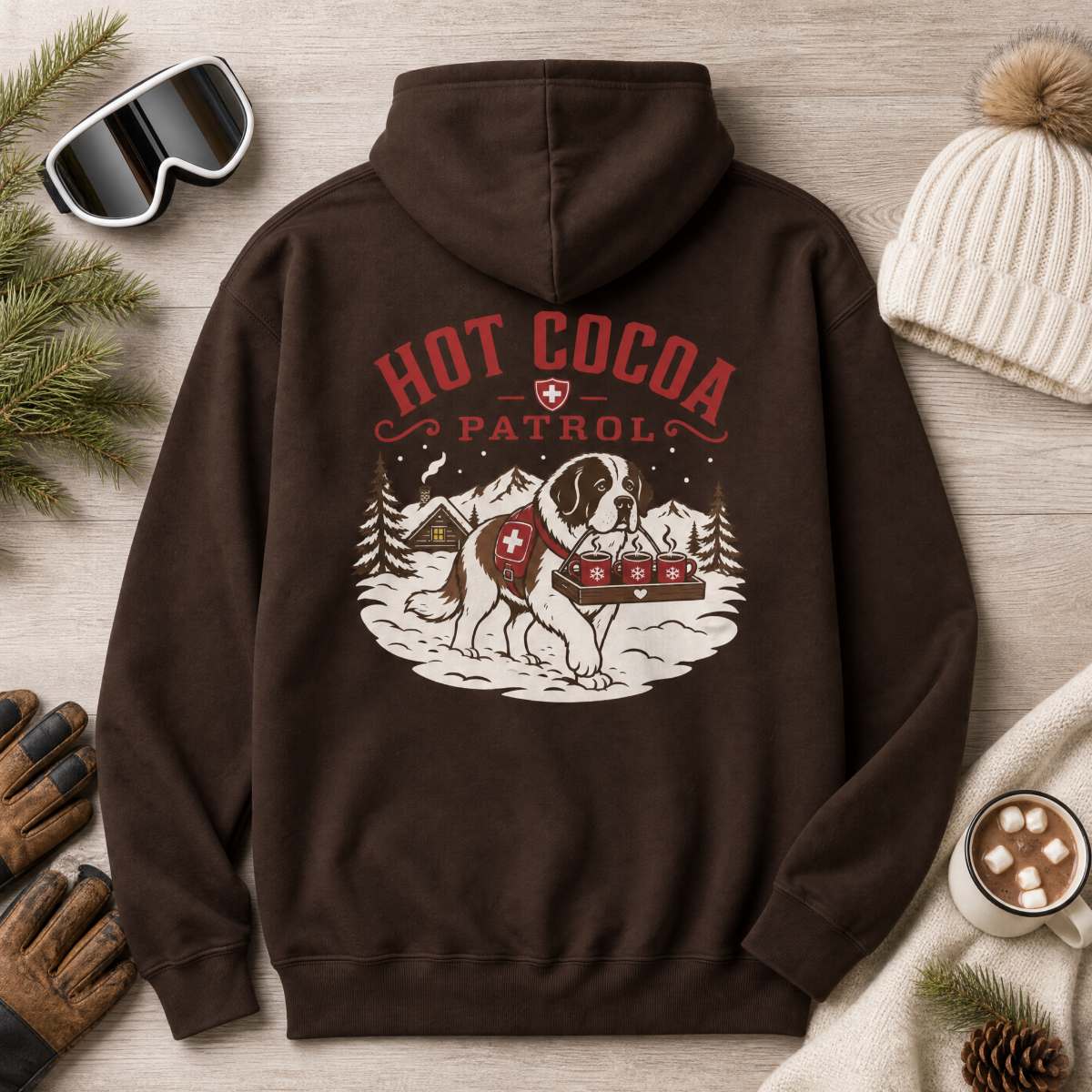 Dark chocolate brown hoodie with 'Hot Cocoa Patrol' graphic on a wooden surface with winter accessories.