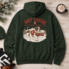 Forest green hoodie with 'Hot Cocoa Patrol' design on a wooden surface with winter decor.