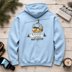 Light blue hoodie with a graphic design on the back, placed on a wooden surface with winter accessories.