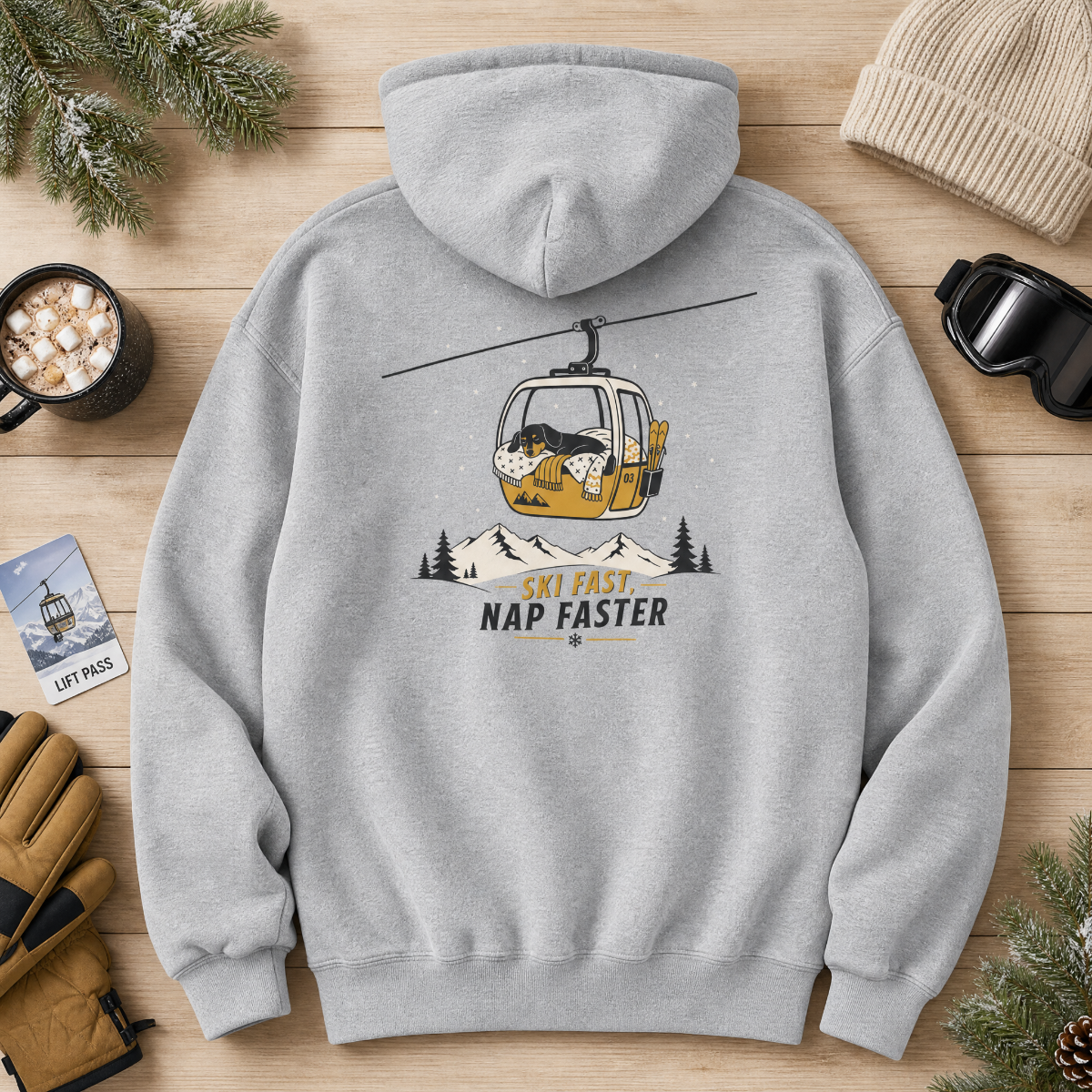 Sport grey hoodie with a ski lift graphic and text on a wooden surface with winter accessories.