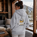 Woman wearing a sport gray hoodie with a mountain graphic in a cozy living room with a snowy mountain view.