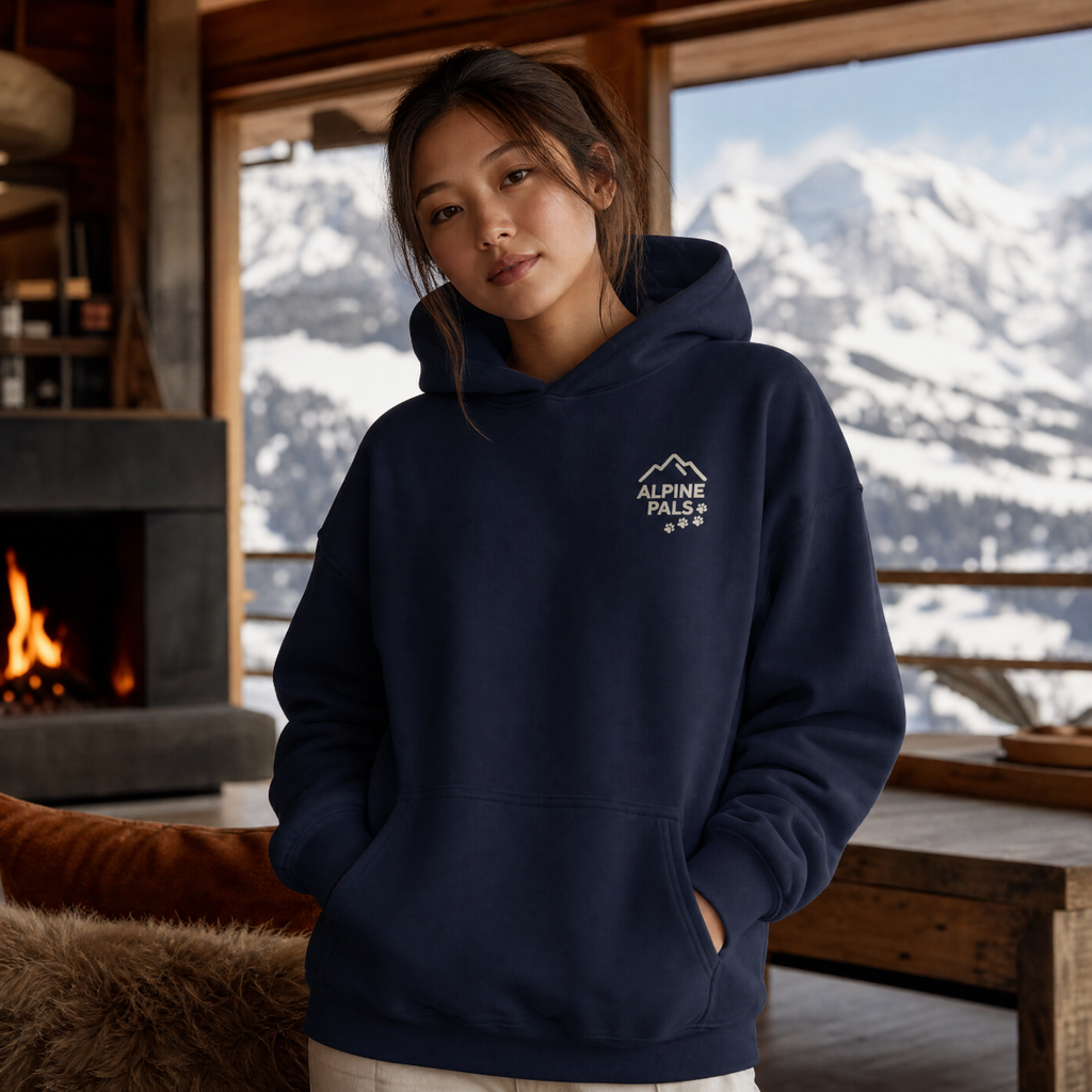 Person wearing a navy hoodie with 'Alpine Pals' logo in a cozy cabin setting.