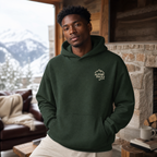 Man wearing a forest green hoodie with a logo in a cozy living room with a mountain view.