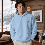 Man wearing a light blue hoodie with 'Alpine Pals' logo in a cozy indoor setting.