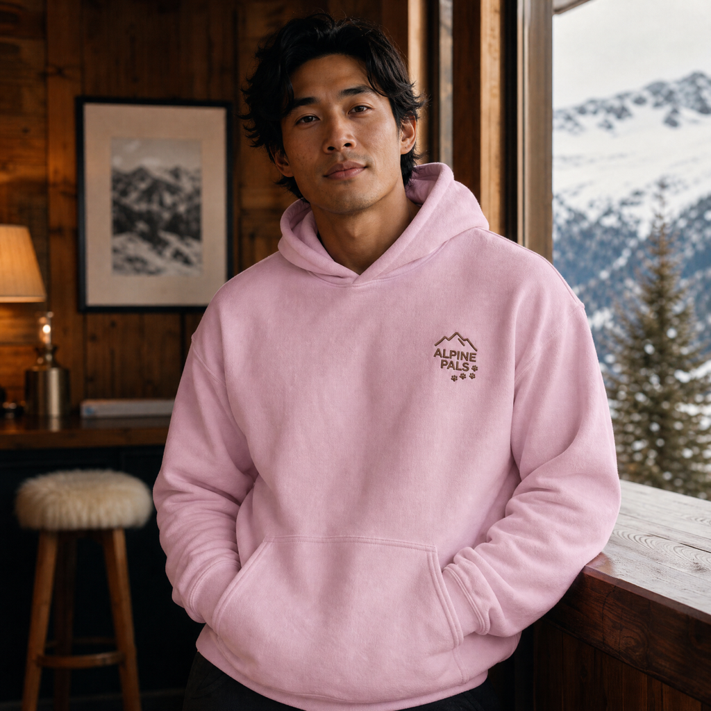 Person wearing a pink hoodie with 'Alpine Pals' logo in a mountainous setting