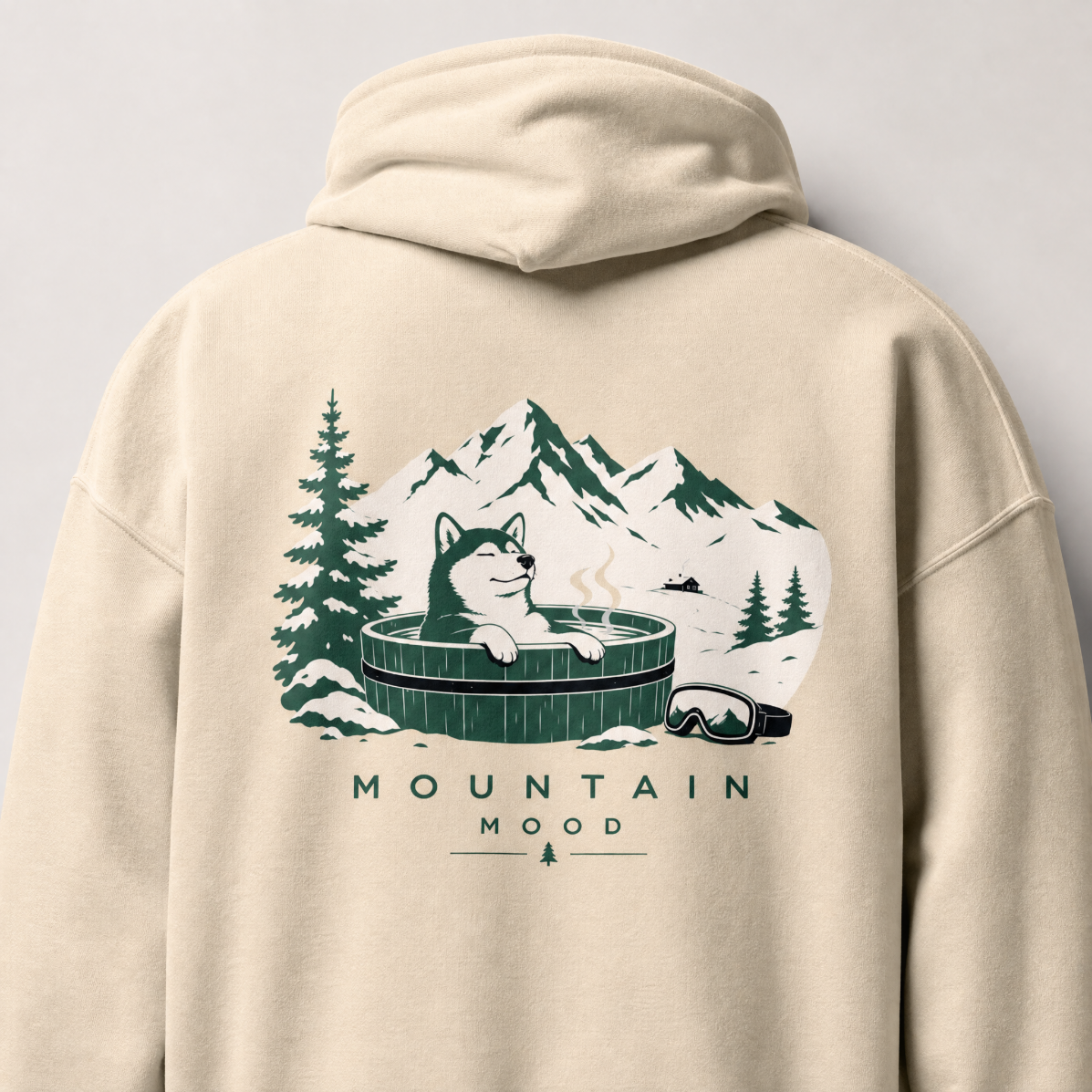 Sand colored hoodie with a graphic of a dog in a hot tub surrounded by mountains and trees on the back.