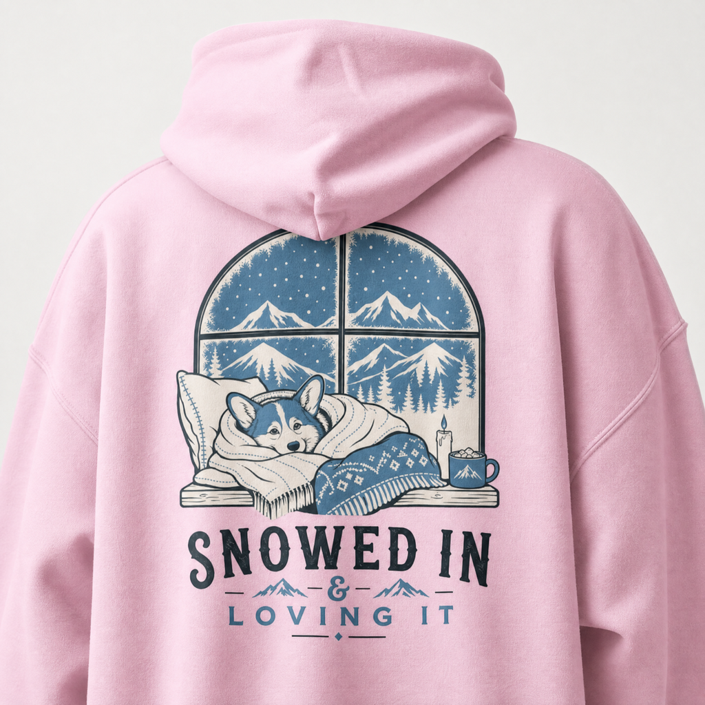Pink hoodie with a graphic of a dog by a window and 'Snowed In & Loving It' text on the back.