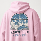 Pink hoodie with a graphic of a dog by a window and 'Snowed In & Loving It' text on the back.