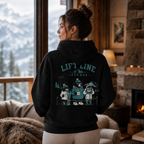Person wearing a black hoodie with 'Lift Line Legends' design, standing in a cozy room with a fireplace and snowy view.