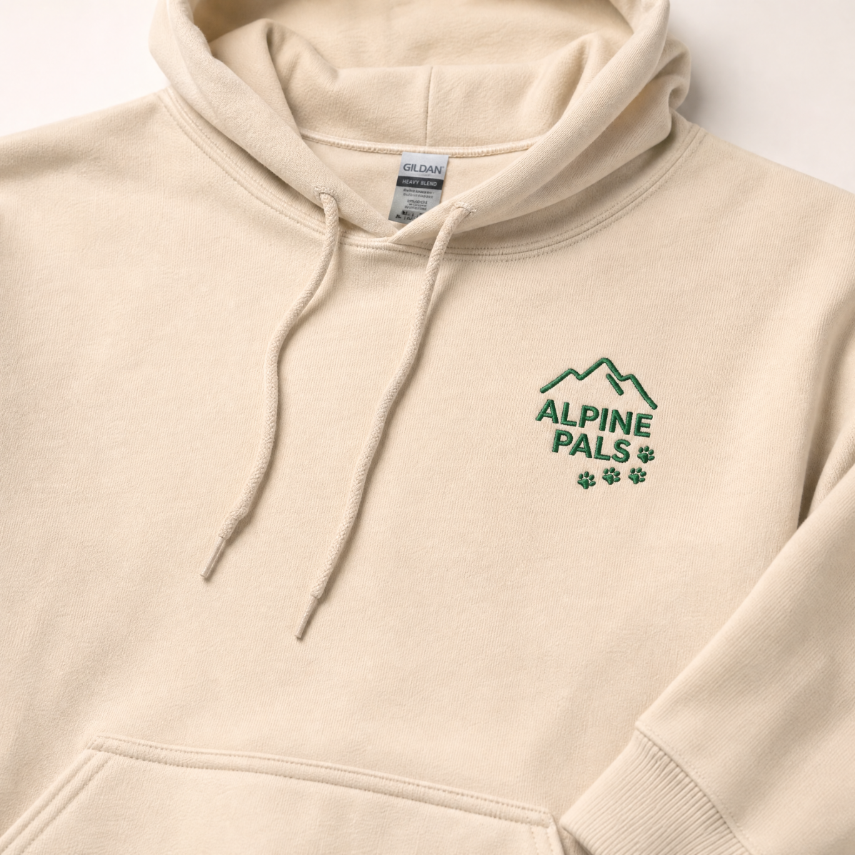 Sand colored hoodie with 'Alpine Pals' logo on a light background