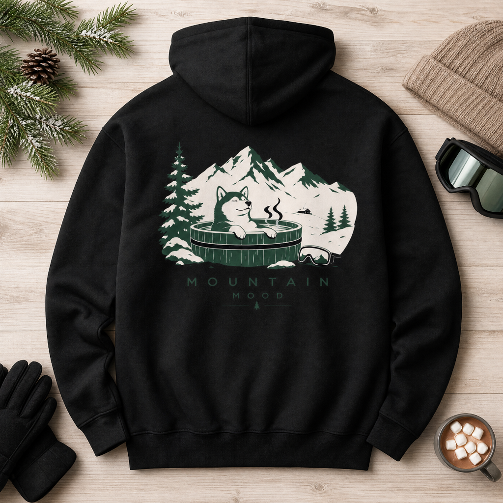 Black hoodie with mountain graphic on a wooden surface with winter accessories.