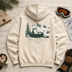 Sand colored hoodie with mountain graphic on a wooden surface with winter accessories.