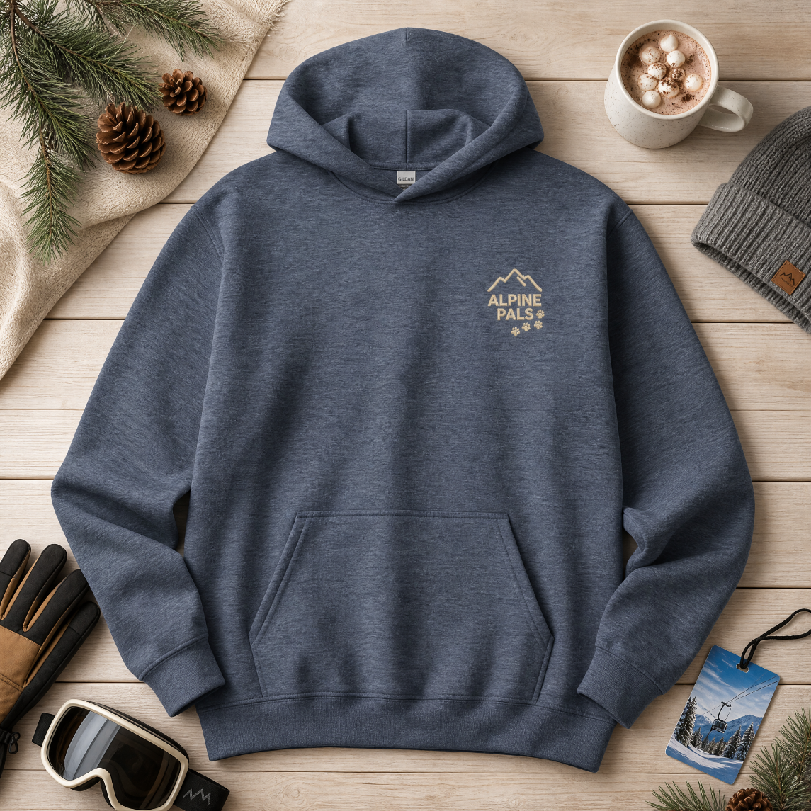 Heather sport dark navy hoodie with 'Alpine Pals' logo on a wooden surface with winter accessories.