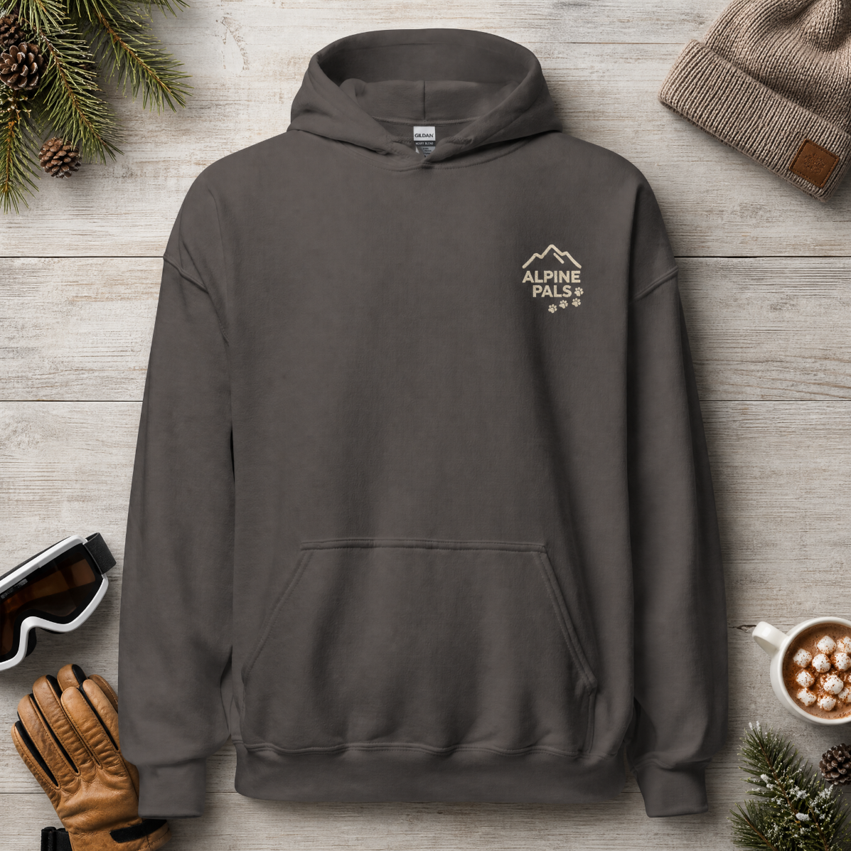 Charcoal gray hoodie with 'Alpine Pals' logo on a wooden surface with winter accessories.