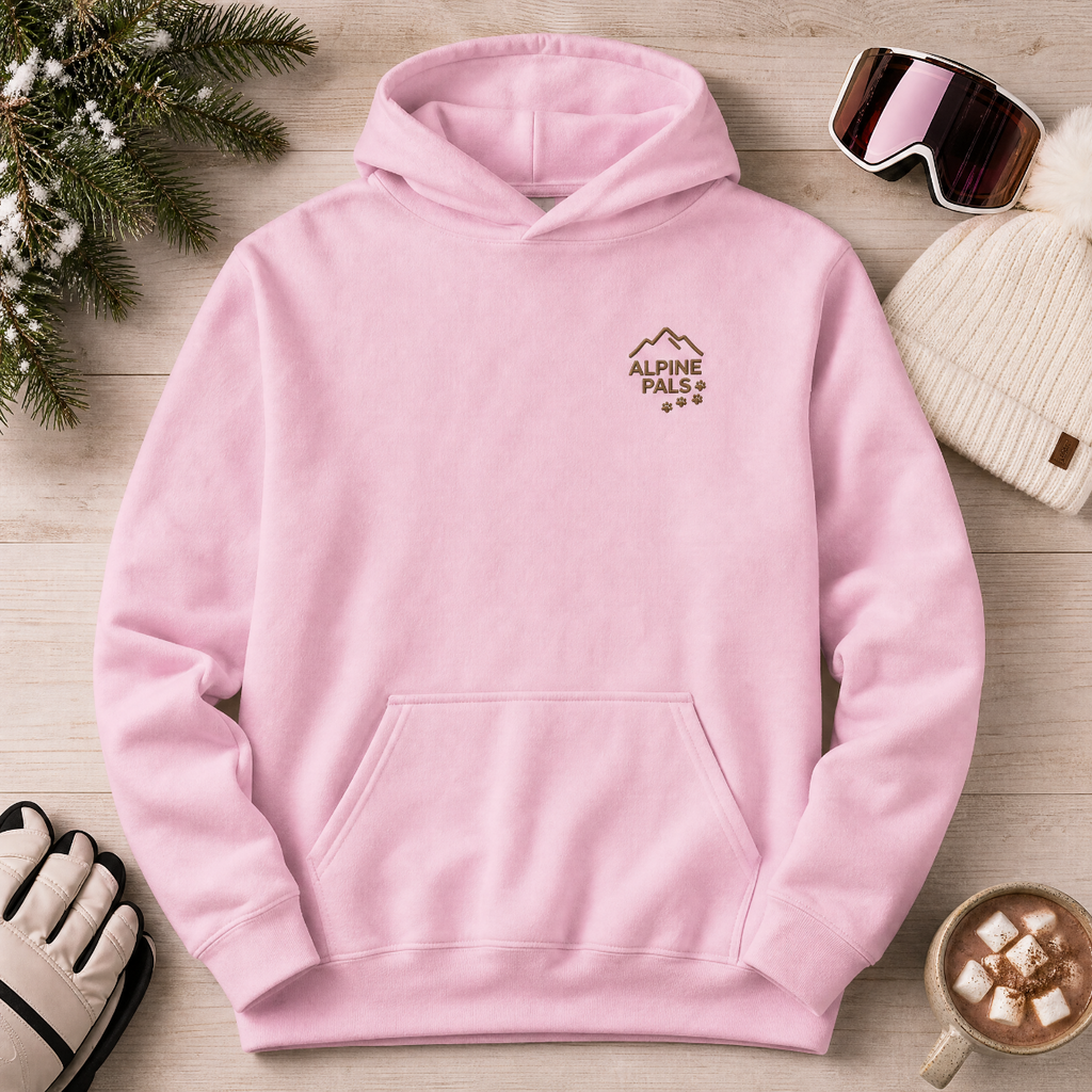 Pink hoodie with 'Alpine Pals' logo on a wooden surface with winter accessories.