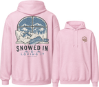 Pink hoodie with a graphic of a dog sleeping under a blanket and mountains, with text 'Snowed In & Loving It' on the front.