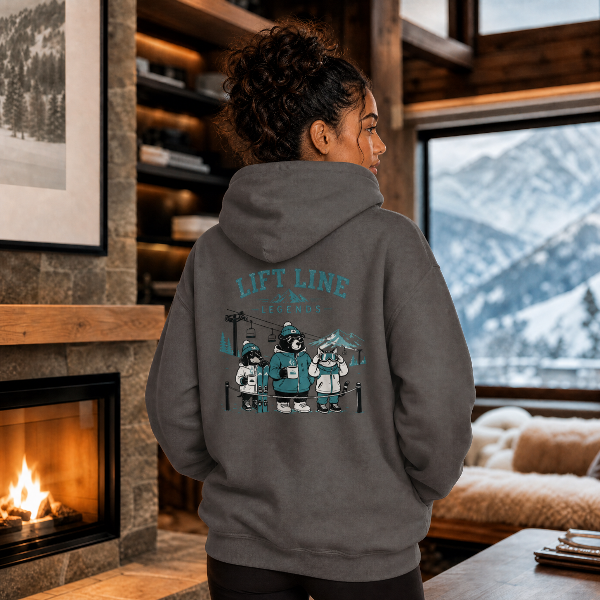 Person wearing a hoodie with a bear graphic and 'Lift Line' text, standing in a cozy room with a fireplace and mountain view.