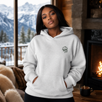 Woman wearing an ash gray hoodie with a logo in a cozy room with a fireplace and mountain view.