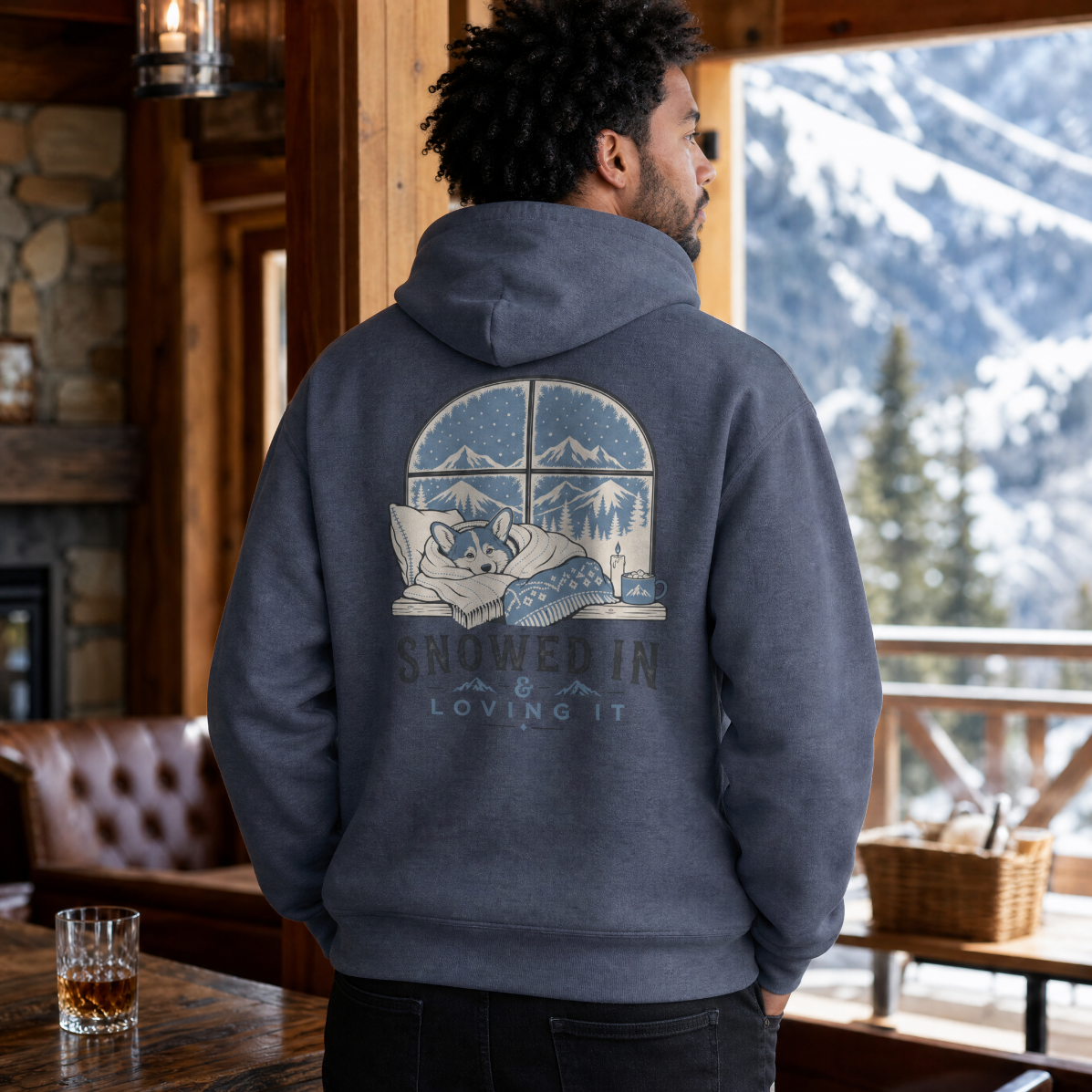 Person wearing a hoodie with a mountain graphic in a cozy cabin setting