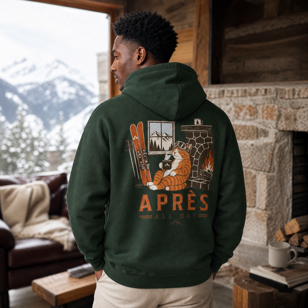 Person wearing a forest green hoodie with a graphic design in a cozy cabin setting