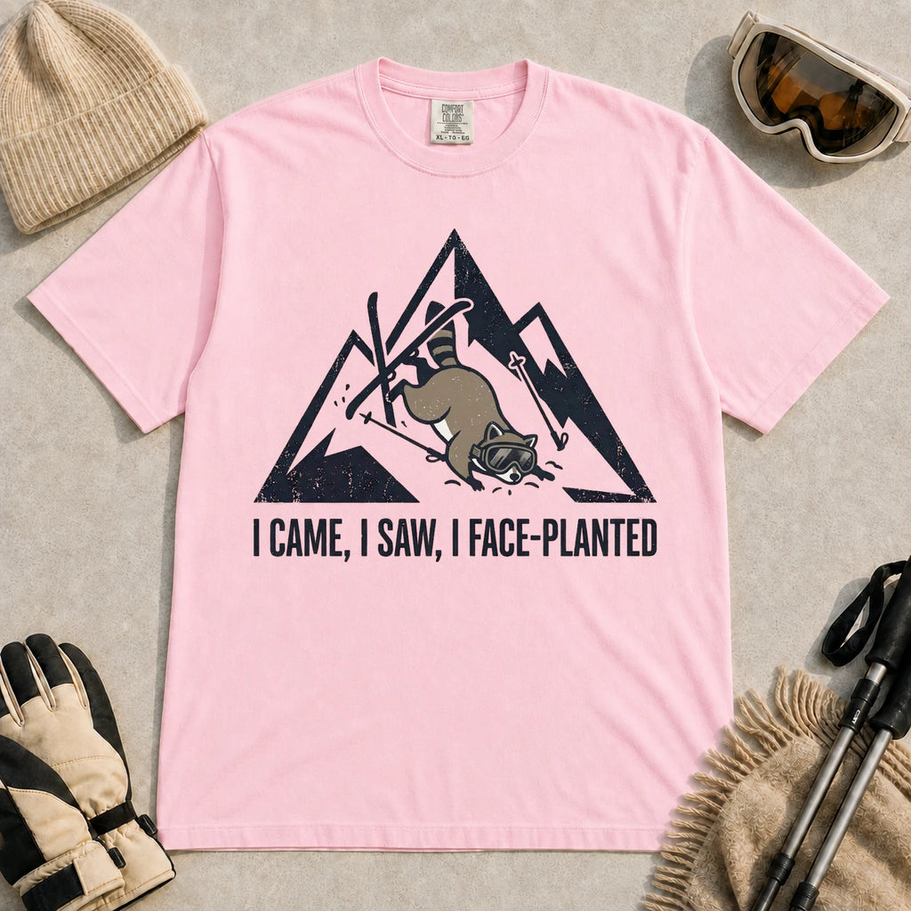 Blossom tee featuring a raccoon face-planting into the snow beneath a distressed mountain graphic with the phrase “I Came, I Saw, I Face-Planted.”