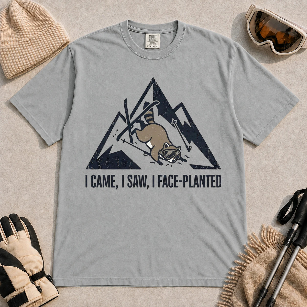 Granite tee featuring a raccoon face-planting into the snow beneath a distressed mountain graphic with the phrase “I Came, I Saw, I Face-Planted.”