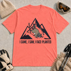 Coral Silk tee featuring a raccoon face-planting into the snow beneath a distressed mountain graphic with the phrase “I Came, I Saw, I Face-Planted.”