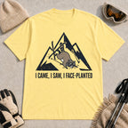 Cornsilk tee featuring a raccoon face-planting into the snow beneath a distressed mountain graphic with the phrase “I Came, I Saw, I Face-Planted.”