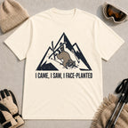 Natural tee featuring a raccoon face-planting into the snow beneath a distressed mountain graphic with the phrase “I Came, I Saw, I Face-Planted.”