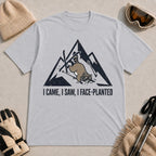 Sport Grey tee featuring a raccoon face-planting into the snow beneath a distressed mountain graphic with the phrase “I Came, I Saw, I Face-Planted.”