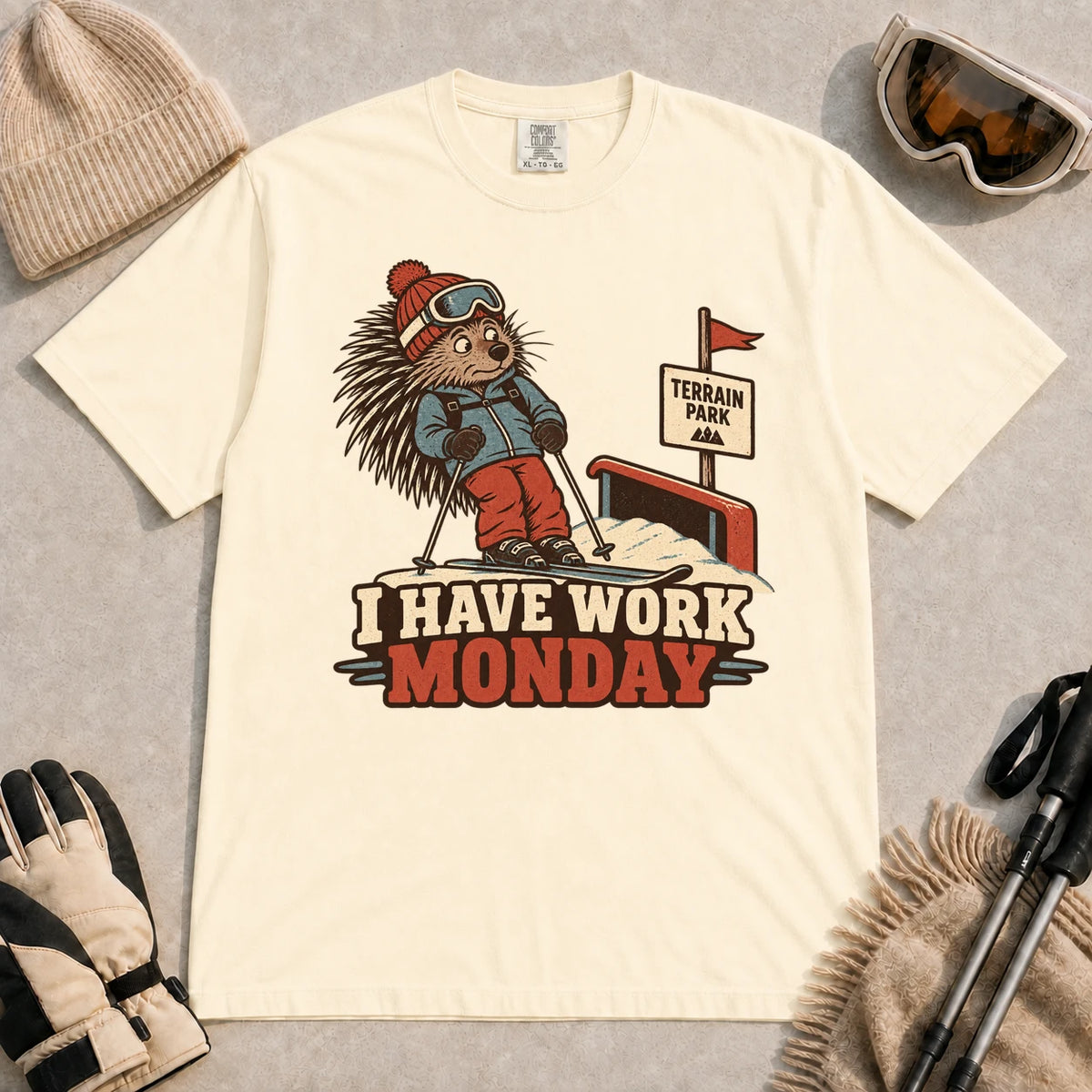 Ivory tee featuring a cautious porcupine skier beside a terrain park rail and sign above the phrase “I Have Work Monday.”