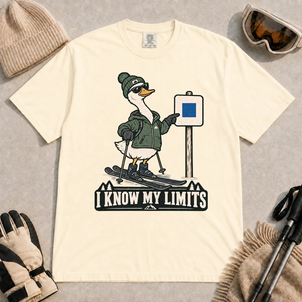 Ivory tee featuring a cool duck skier pointing to a blue-square trail sign above the phrase “I Know My Limits.”