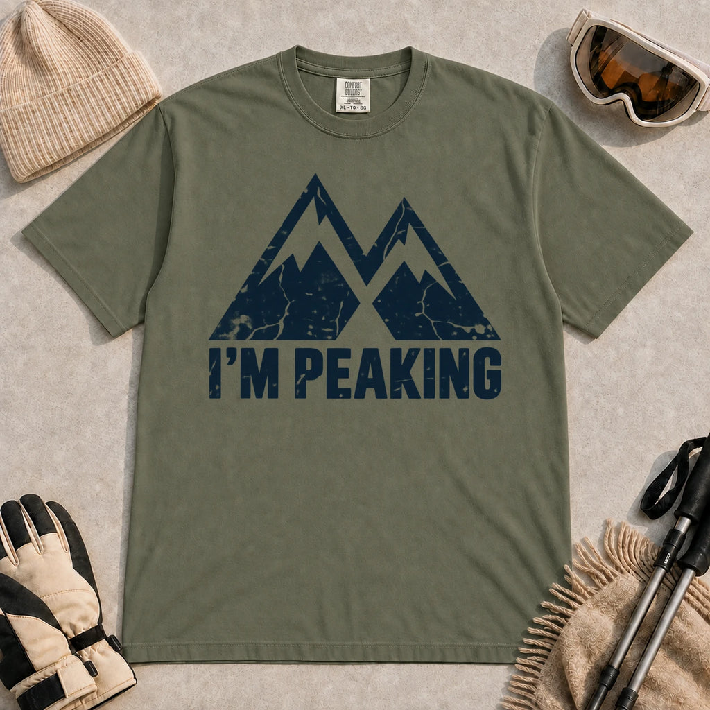 Moss tee featuring a distressed navy double-mountain graphic above the phrase “I’m Peaking.”