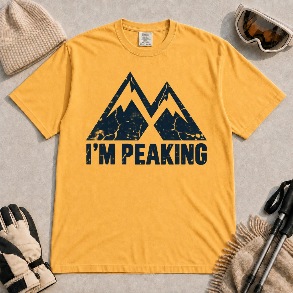Mustard tee featuring a distressed navy double-mountain graphic above the phrase “I’m Peaking.”