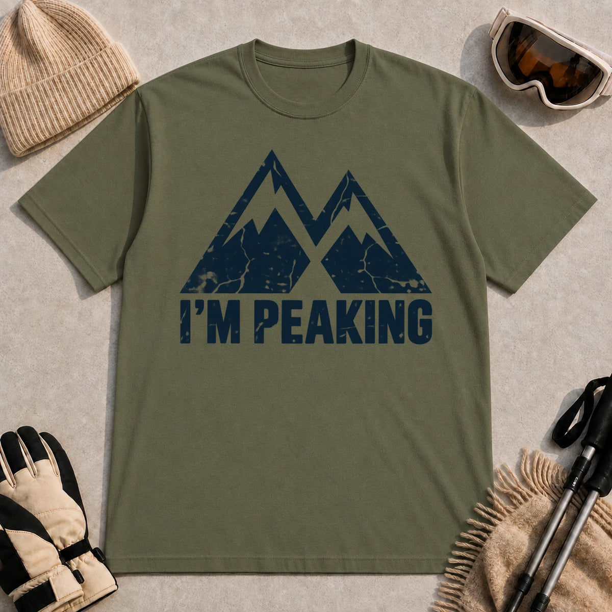 Military Green tee featuring a distressed navy double-mountain graphic above the phrase “I’m Peaking.”