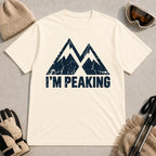 Natural tee featuring a distressed navy double-mountain graphic above the phrase “I’m Peaking.”