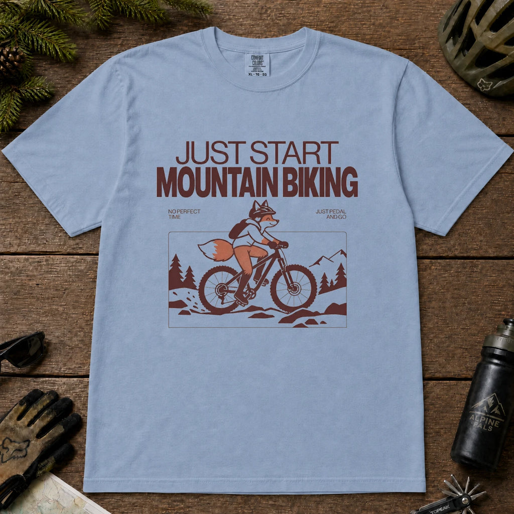 Washed Denim tee featuring a fox mountain biking through a minimalist trail scene with the phrases “Just Start Mountain Biking,” “No Perfect Time,” and “Just Pedal and Go.”